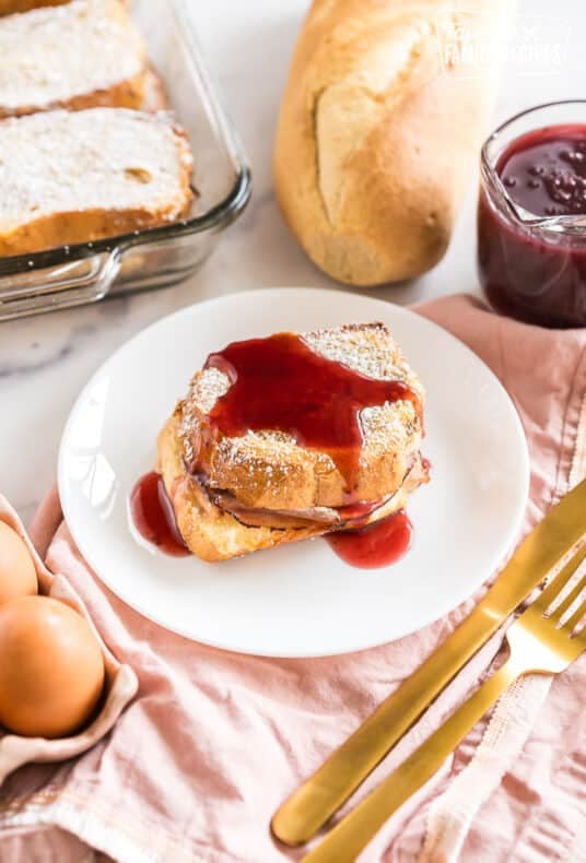 A slice of monte cristo casserole on a plate topped with berry syrup