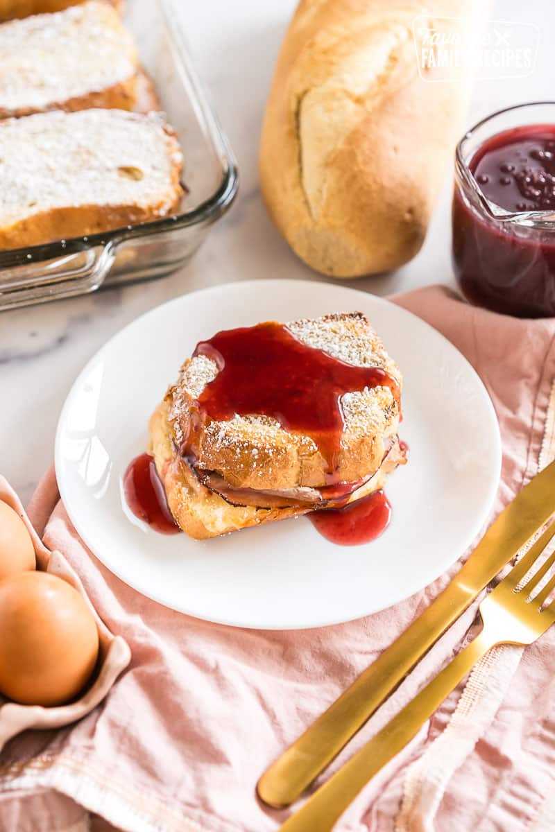 A slice of monte cristo casserole on a plate topped with berry syrup