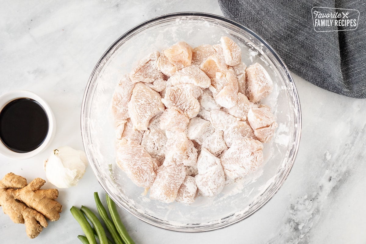 Mixing bowl with cut up pieces of chicken coated with corn starch.