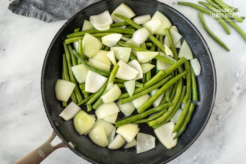 Skillet with green beans and onion cut up for Panda Express String Bean Chicken.