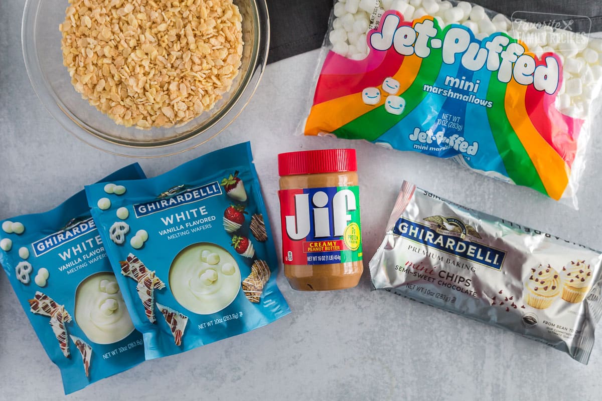 Ingredients for peanut butter bark including marshmallows, crispy rice cereal, peanut butter, white chocolate melting wafers and mini chocolate chips.