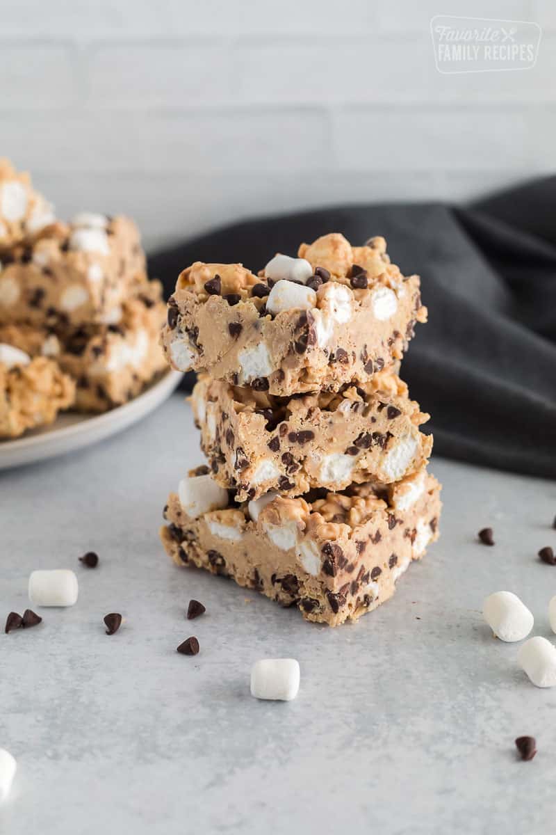 A stack of peanut butter bark and a plate of them in the background.