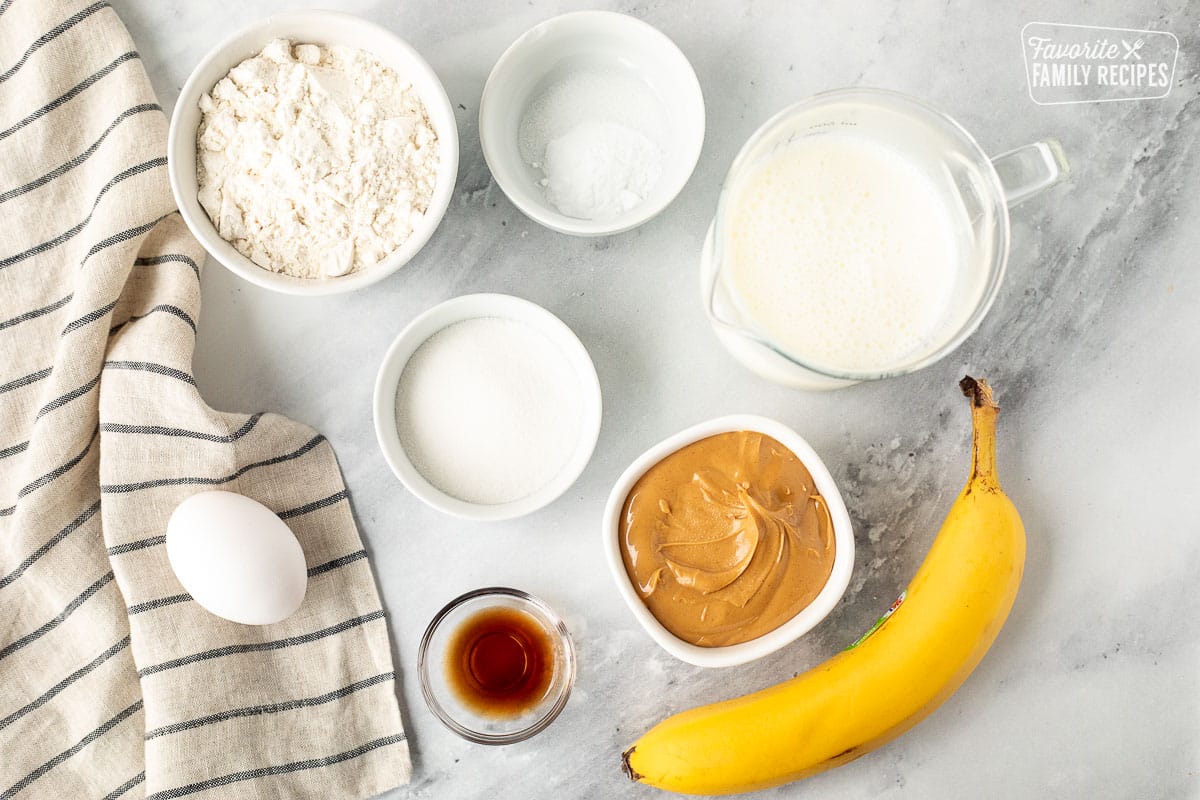 Ingredients to make Peanut Butter Pancakes including flour, sugar, salt, baking soda, buttermilk, peanut butter, vanilla and egg.