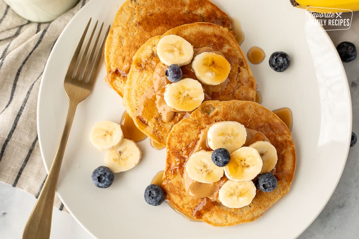 Plate with Peanut Butter Pancakes with peanut butter, bananas, blueberries and maple syrup.