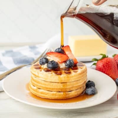 Pouring Maple Syrup over waffles and berries.