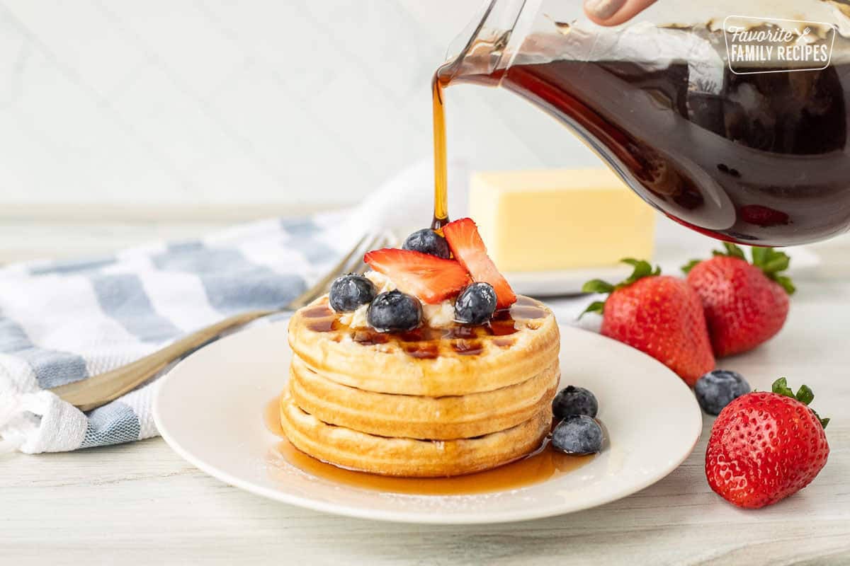 Pouring Maple Syrup over waffles and berries.