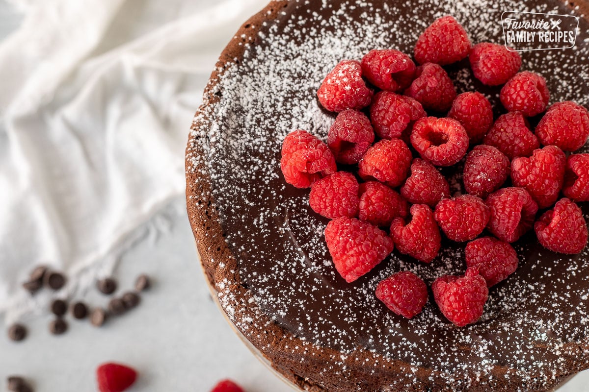 Whole Gluten Free Chocolate Cake with fresh raspberries and powdered sugar dusted on top.
