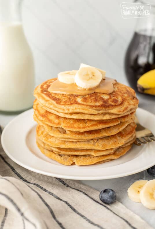 Stack of Peanut Butter Pancakes with peanut butter and sliced banana on top.
