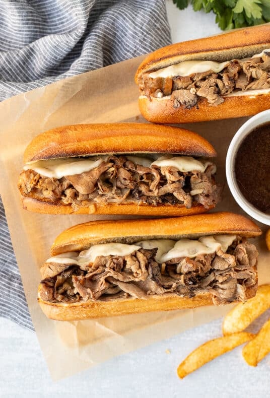 Three French Dip Sandwiches with roast beef and melted cheese.