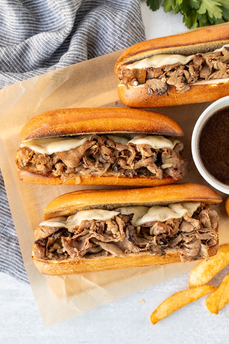 Three French Dip Sandwiches with roast beef and melted cheese.