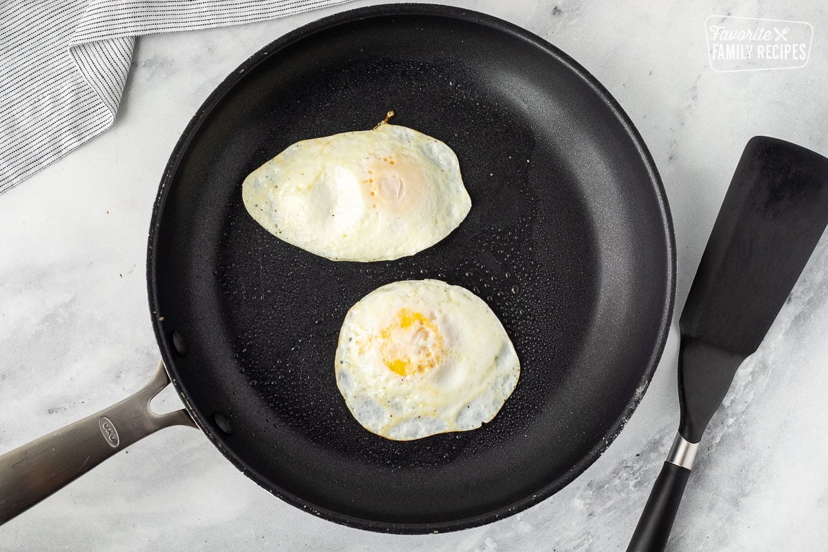 Skillet with two cooked eggs. Spatula on the side.