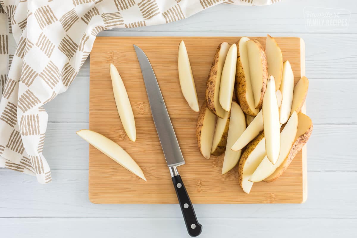 Potatoes on a cutting board that have scrubbed and cut into wedges
