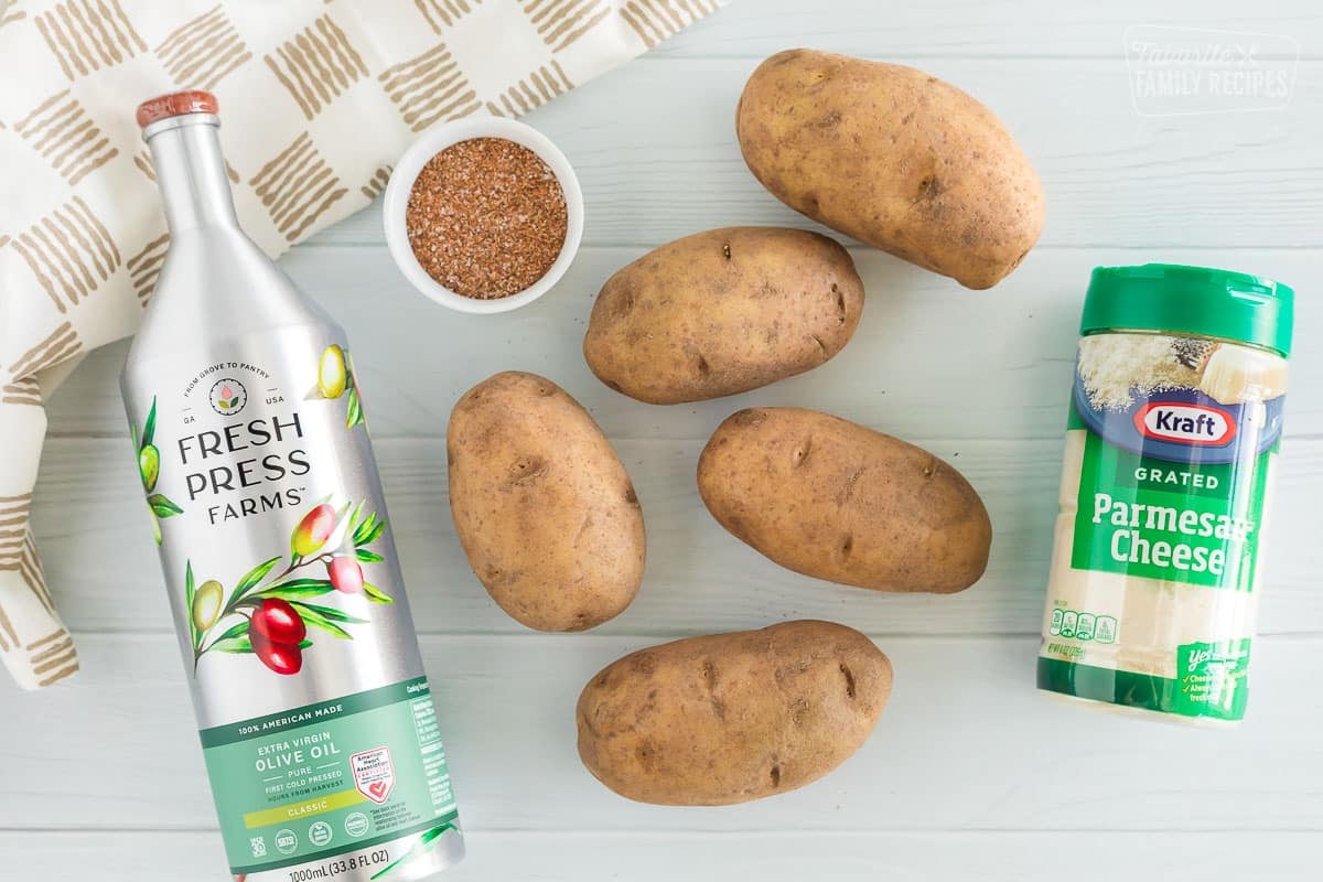 Ingredients for Baked Potato wedges including olive oil, potatoes, seasoning salt and parmesan cheese