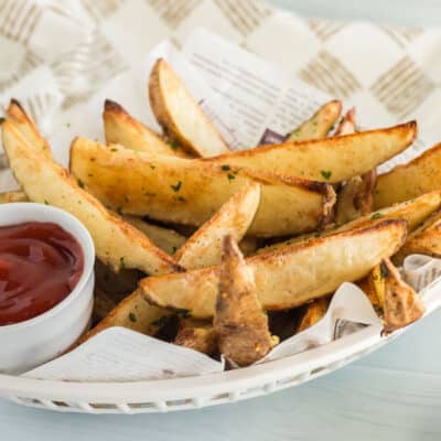 Baked potato wedges in a fry basket with ketchup