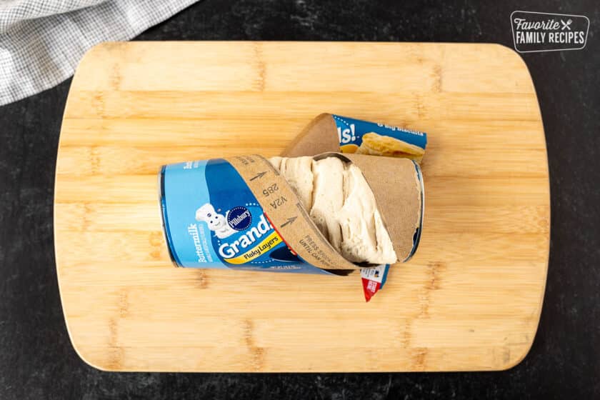 Cutting board with an open can of biscuits.