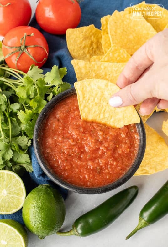 Hand dipping a tortilla chip in a bowl of Chili's Salsa.