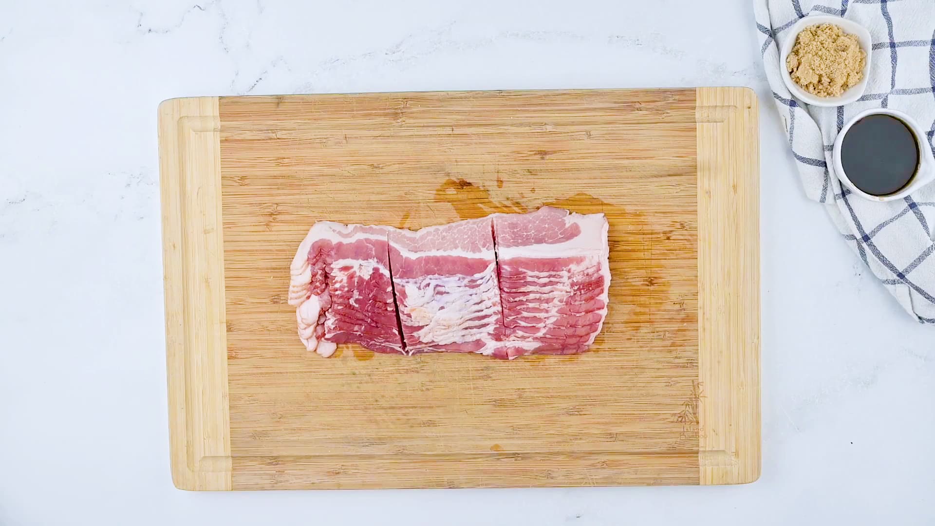 Bacon cut into thirds on a cutting board.