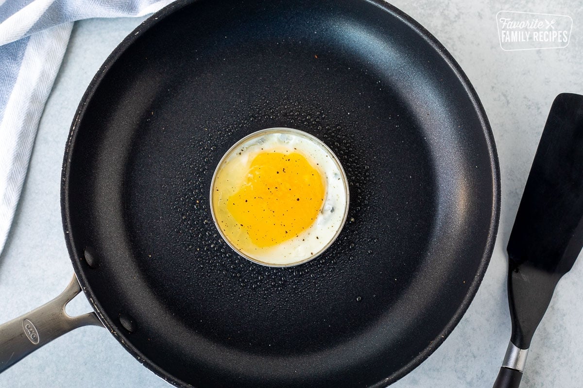 Skillet with egg cooking in a mason jar ring. Spatula on the side.