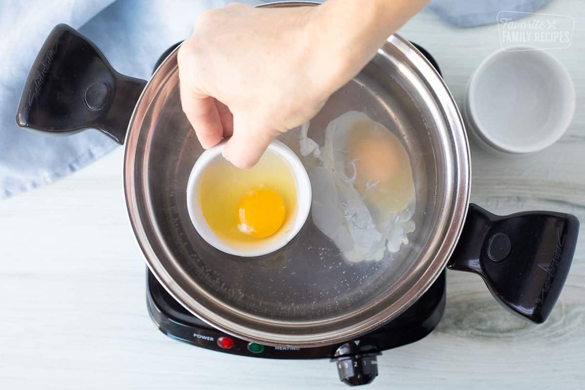 eggs being placed in a pot of boiling water to poach