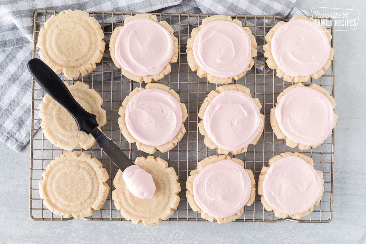 Frosting Swig Cookies with pink frosting on a cooling rack.