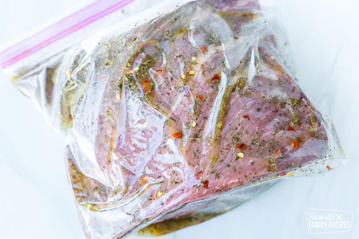 A beef roast marinating in a plastic Ziplock bag