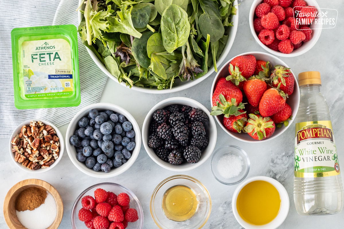 Ingredients to make Nuts About Berries Salad including spring mix, raspberries, blueberries, strawberries, blackberries, pecans, cinnamon, sugar, honey, salt, olive oil, white wine vinegar and feta.