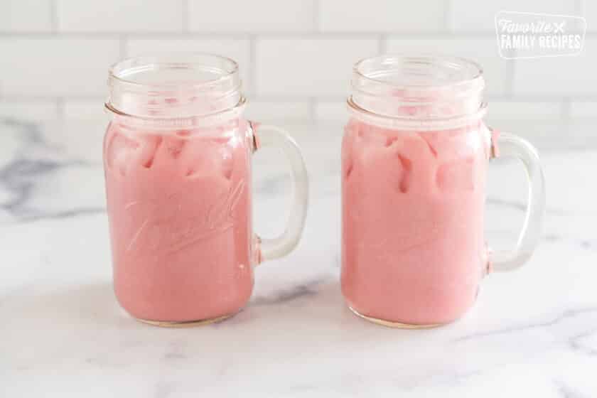 Blended strawberries, juice, sugar, ice and coconut milk in two mason jars