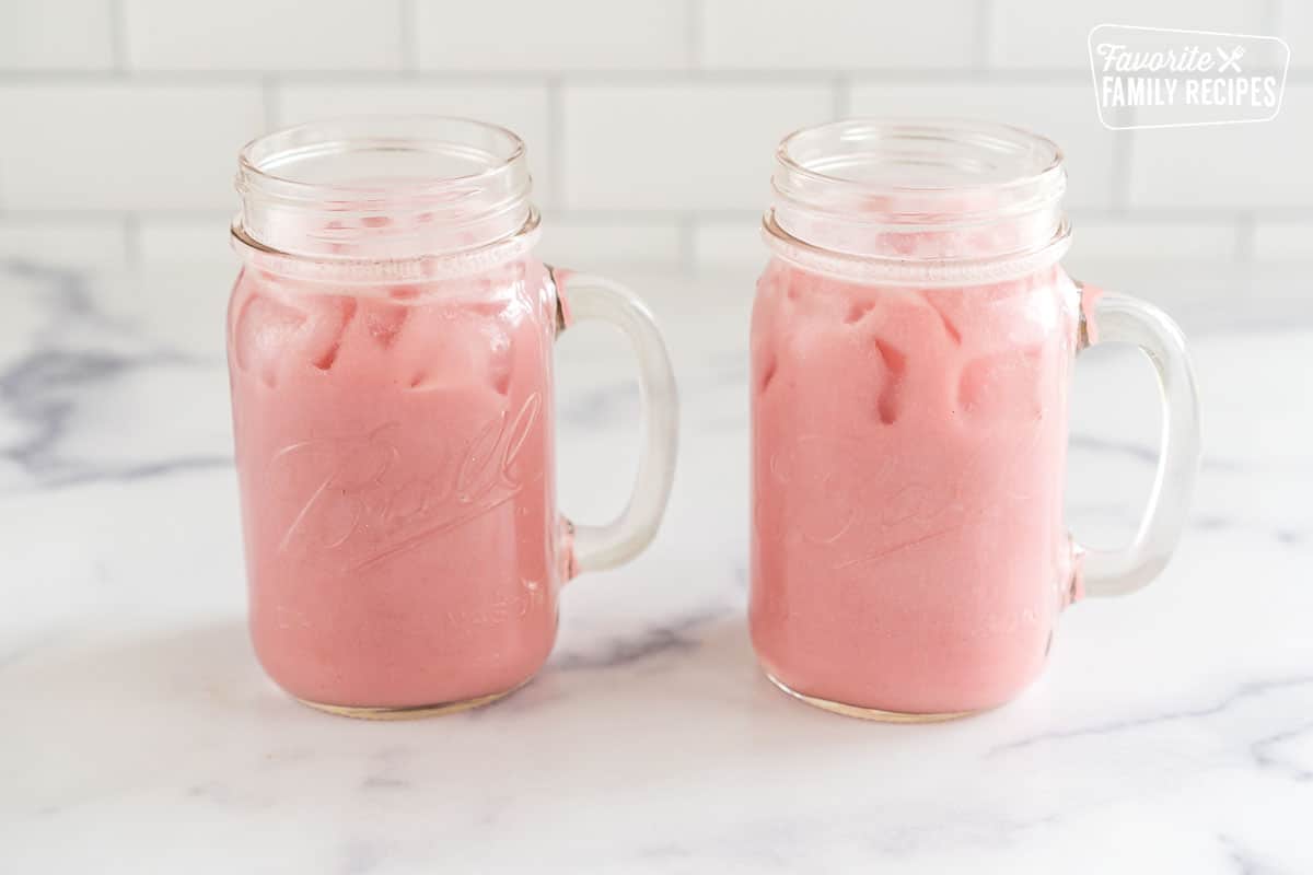 Blended strawberries, juice, sugar, ice and coconut milk in two mason jars