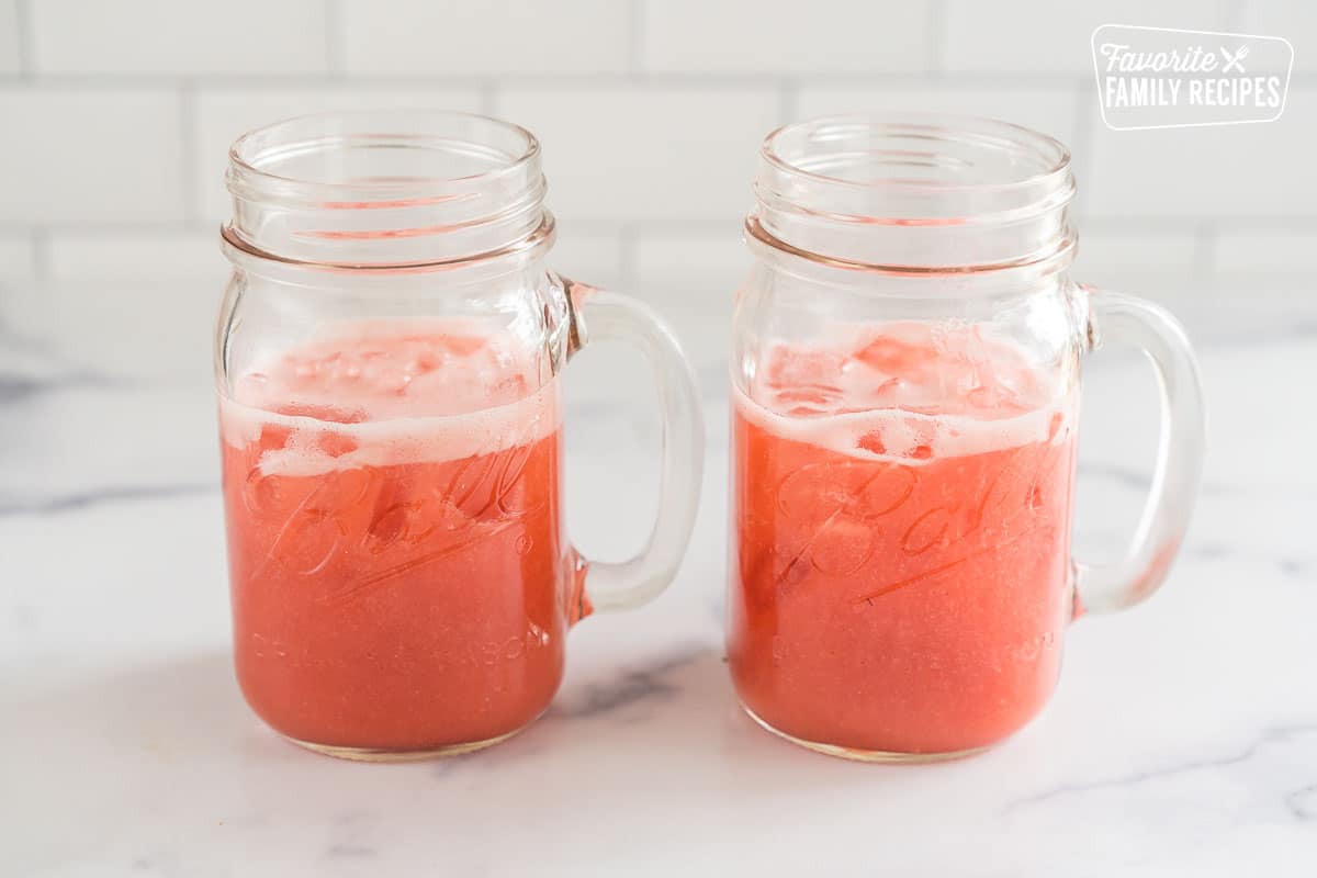 Blended strawberries, juice, and sugar, poured over ice in two mason jars