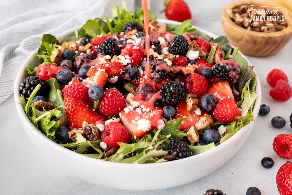 Pouring dressing on a Nuts About Berries Salad.