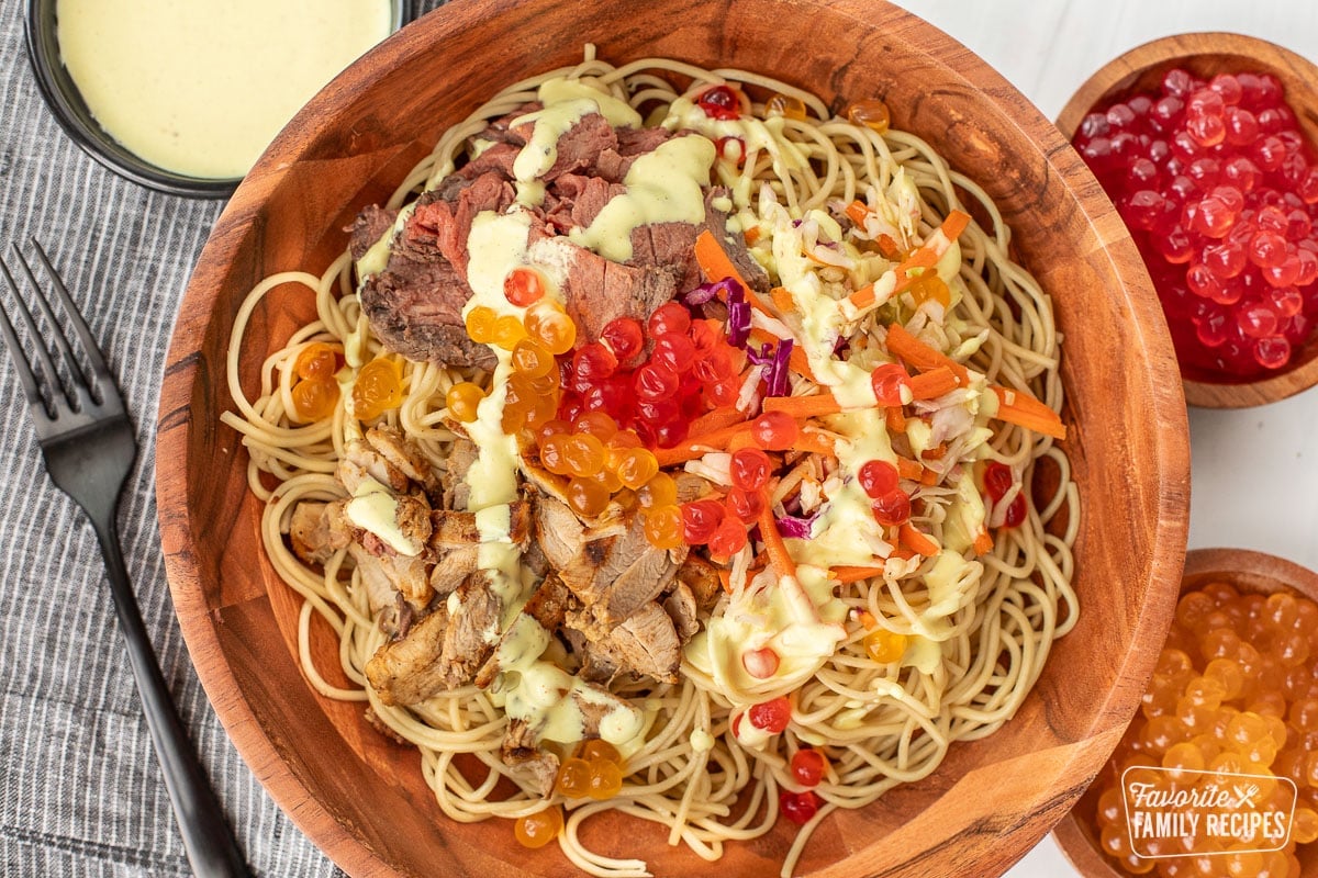 A copycat Satu'li bowl recipe in a wooden bowl next to cups of boba balls with dressing over the top