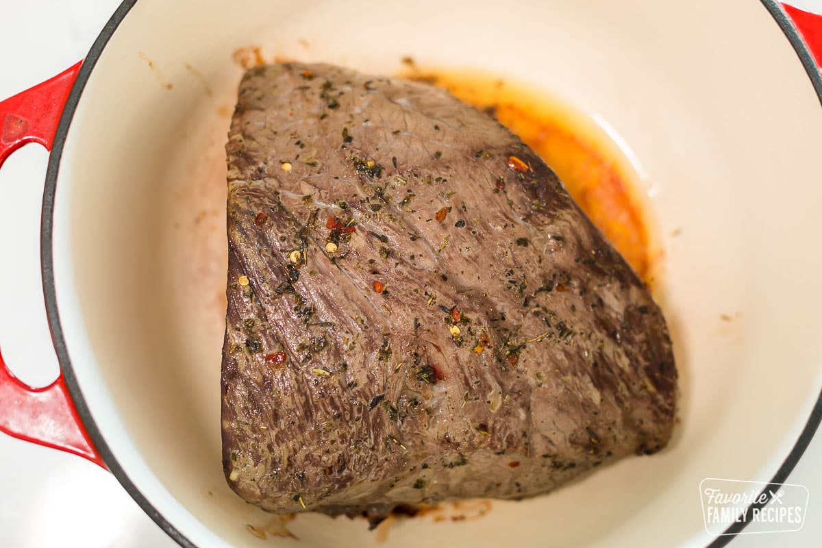 A cooked marinated roast in a roasting pan