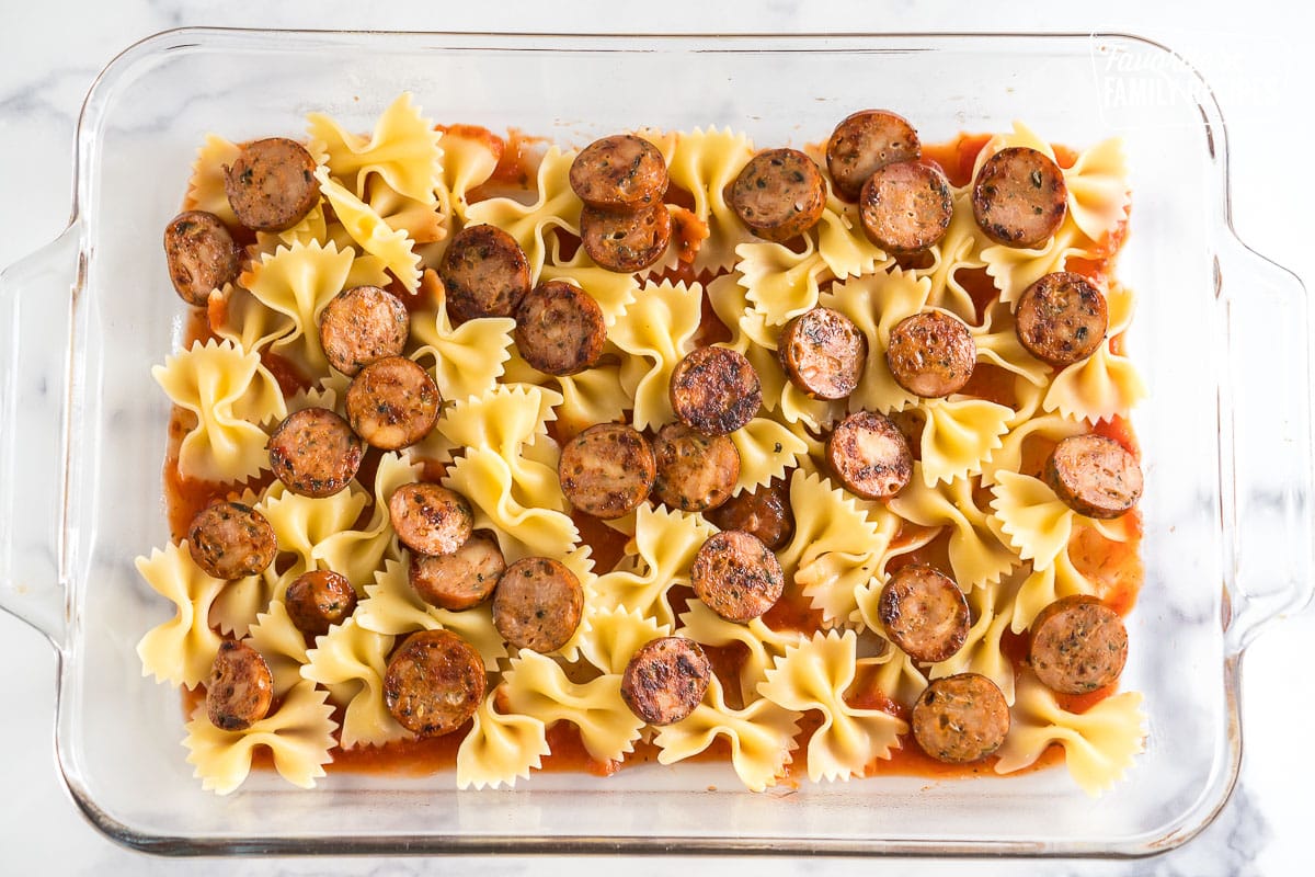 tomato sauce, noodles, and sausage layered in a baking dish