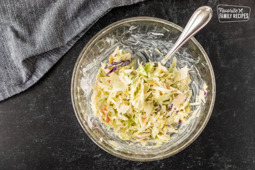 Mixing coleslaw in a bowl with a spoon.
