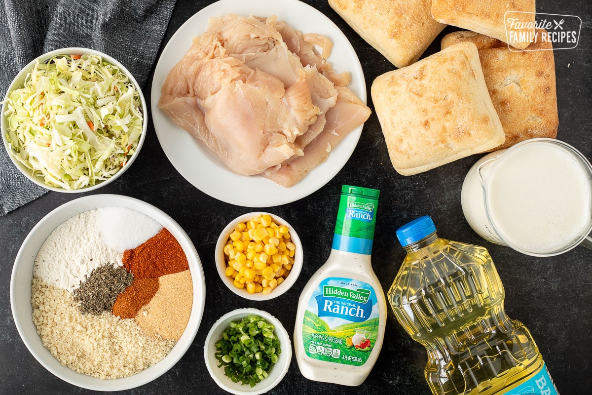 Ingredients to make Southern Fried Chicken Sandwich including flat chicken breasts, cabbage, seasonings, panko, corn, green onion, ranch, oil, buttermilk and ciabatta rolls.