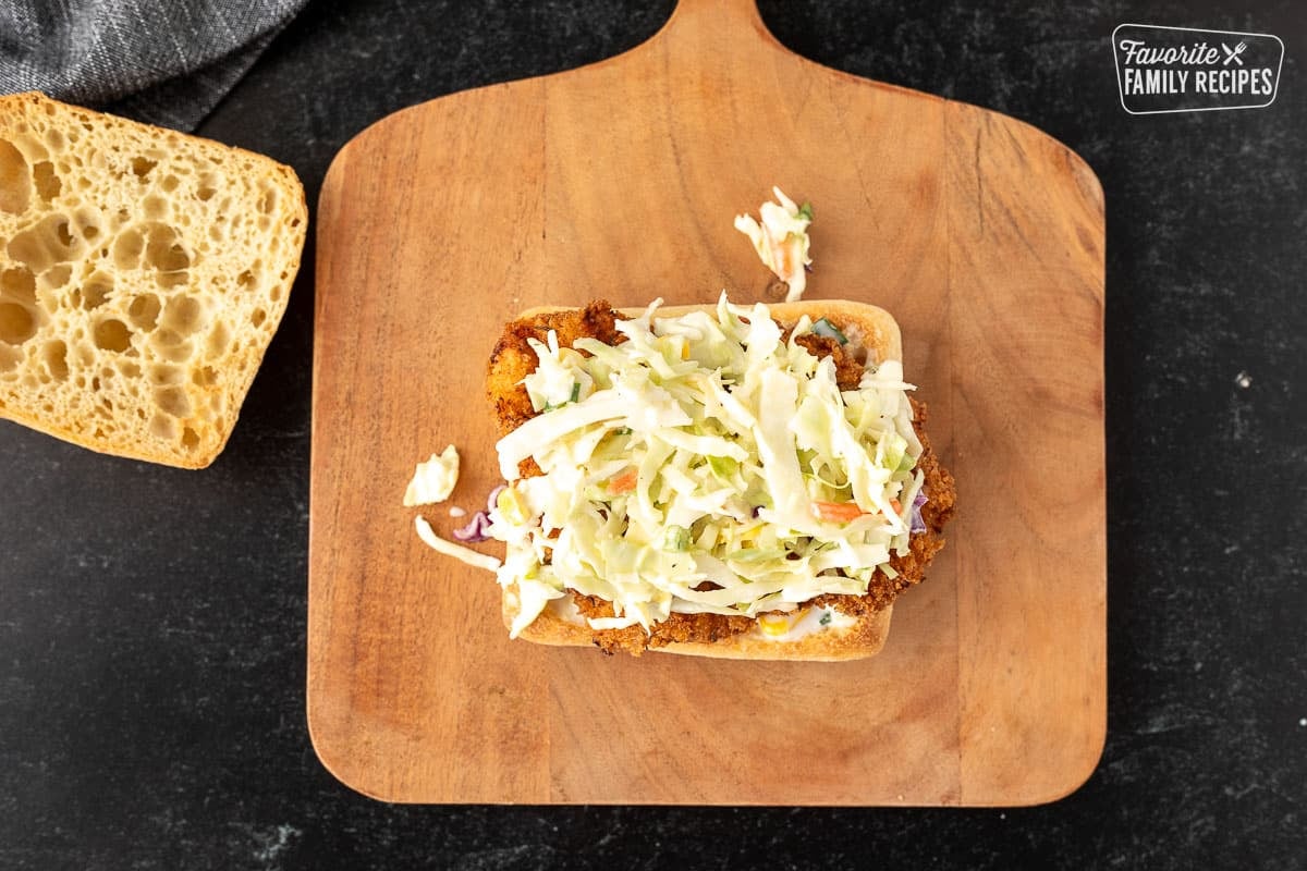 Cole slaw on top of fried chicken and ciabatta roll.