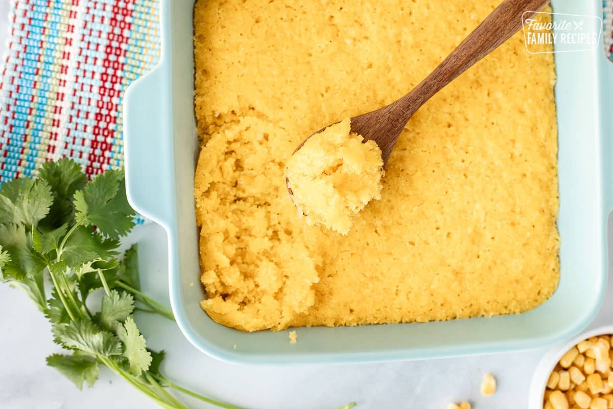 Spoon resting in a casserole dish of baked Sweet Corn Cakes (Tomalitos).