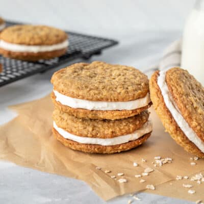 Two stacked Oatmeal Cream Pies next to a leaning Oatmeal Cream Pie cookie.