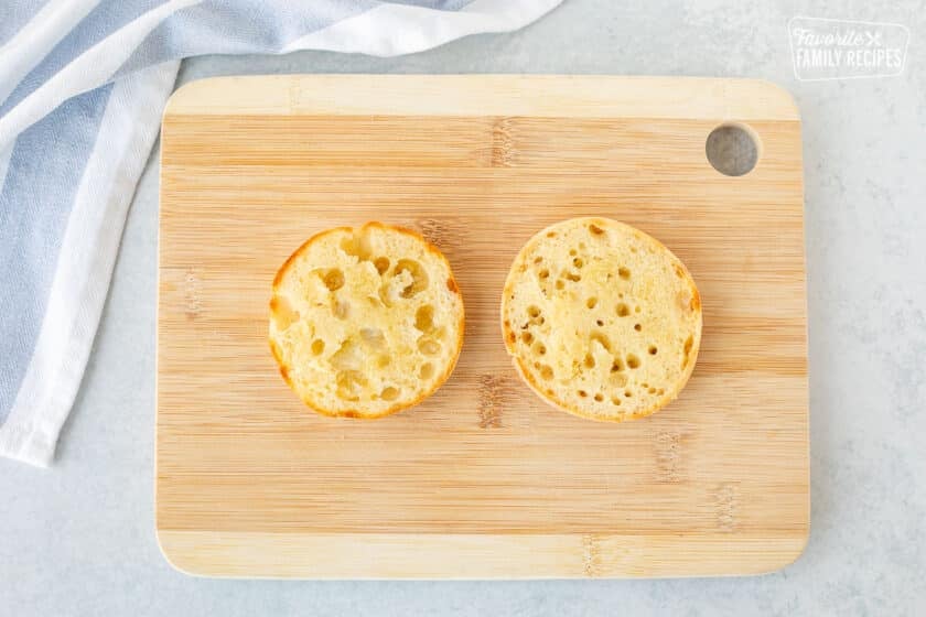 Cutting board with toasted and buttered English muffin.