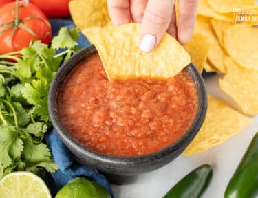 Hand dipping a tortilla chip into a bowl of Chili's Salsa.