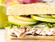 Turkey sandwich with fig butter, brie cheese, greens, apples and dijon mustard on a French baguette.