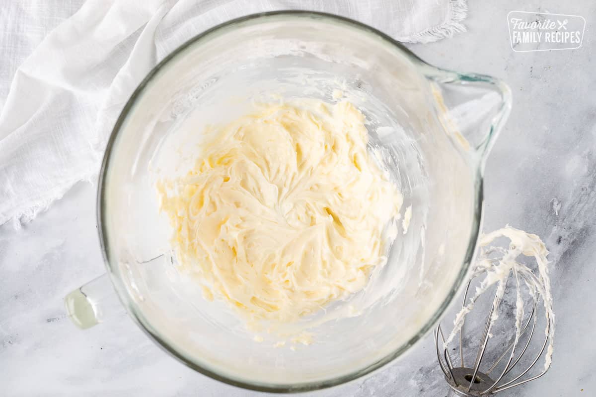 Mixing bowl of whipped butter and shortening with whisk attachment on the side.