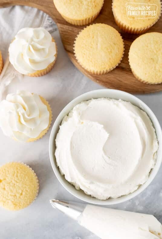 Bowl of Vanilla Buttercream Frosting with vanilla cupcakes.