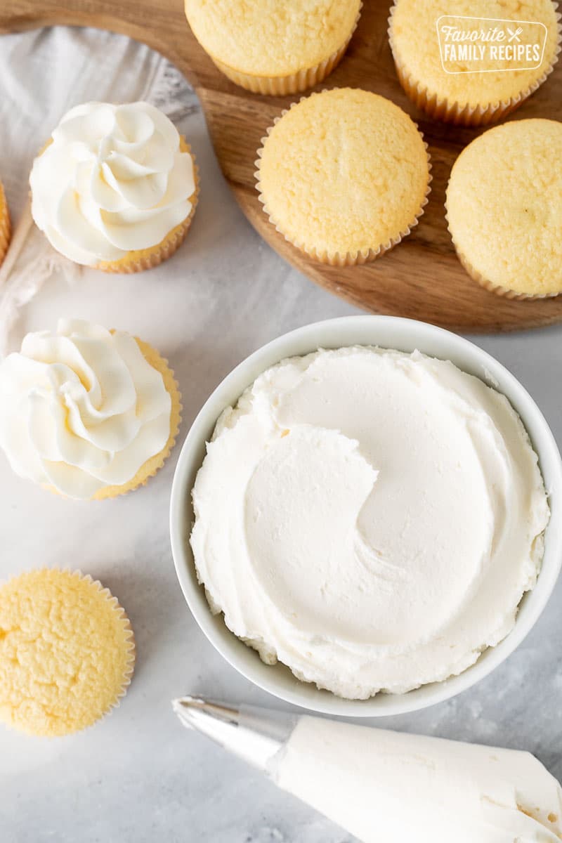 Bowl of Vanilla Buttercream Frosting with vanilla cupcakes.