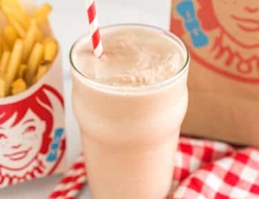 Wendy's frosty in a glass cup with a striped straw