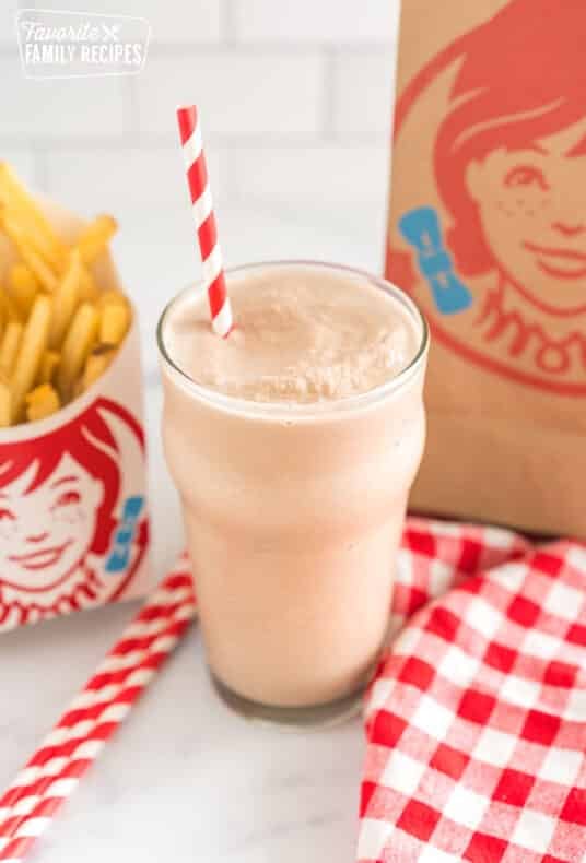 Wendy's frosty in a glass cup with a striped straw