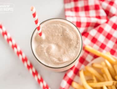 Wendy's frosty in a glass cup with a striped straw