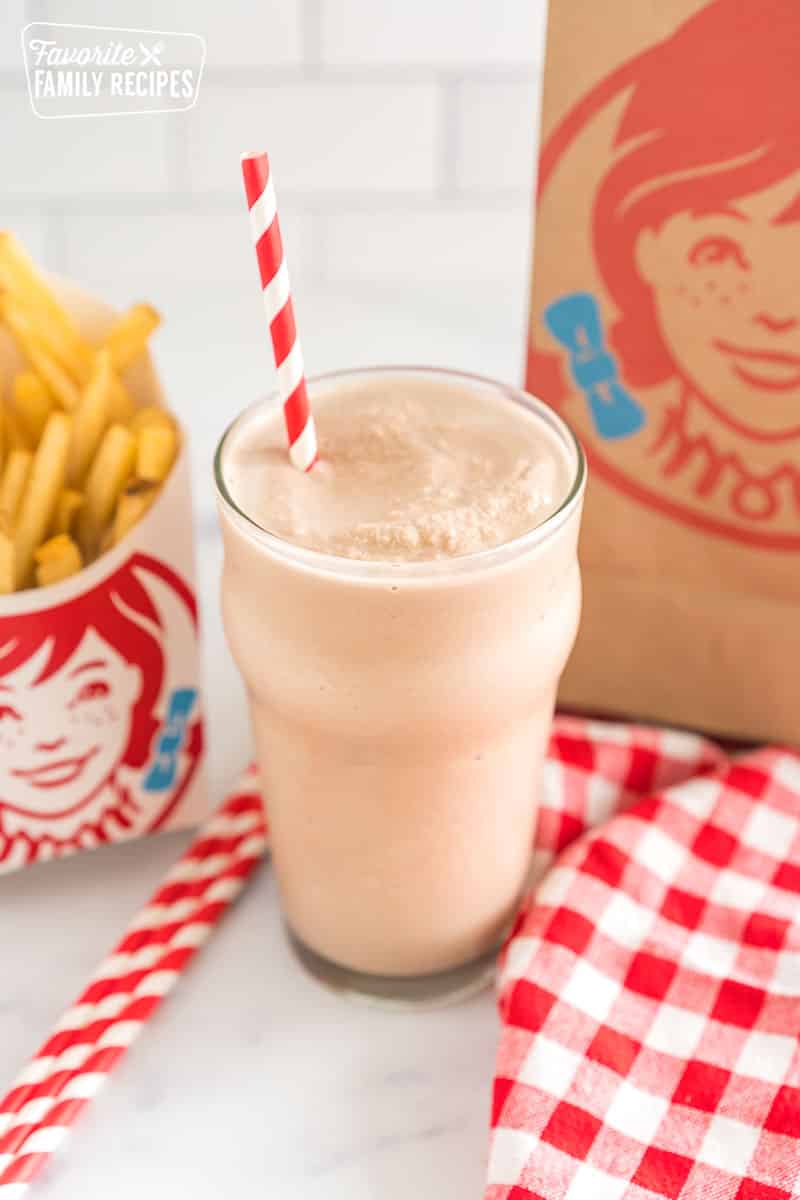 Wendy's frosty in a glass cup with a striped straw