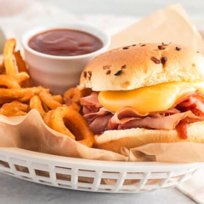 Arby's ham and cheddar melt inside a basket with curly fries and Arby's sauce
