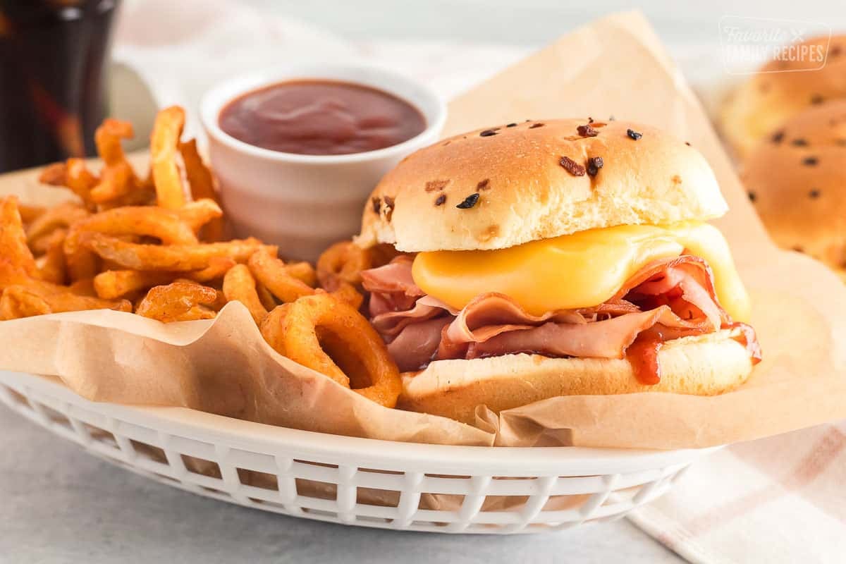 Arby's ham and cheddar melt inside a basket with curly fries and Arby's sauce